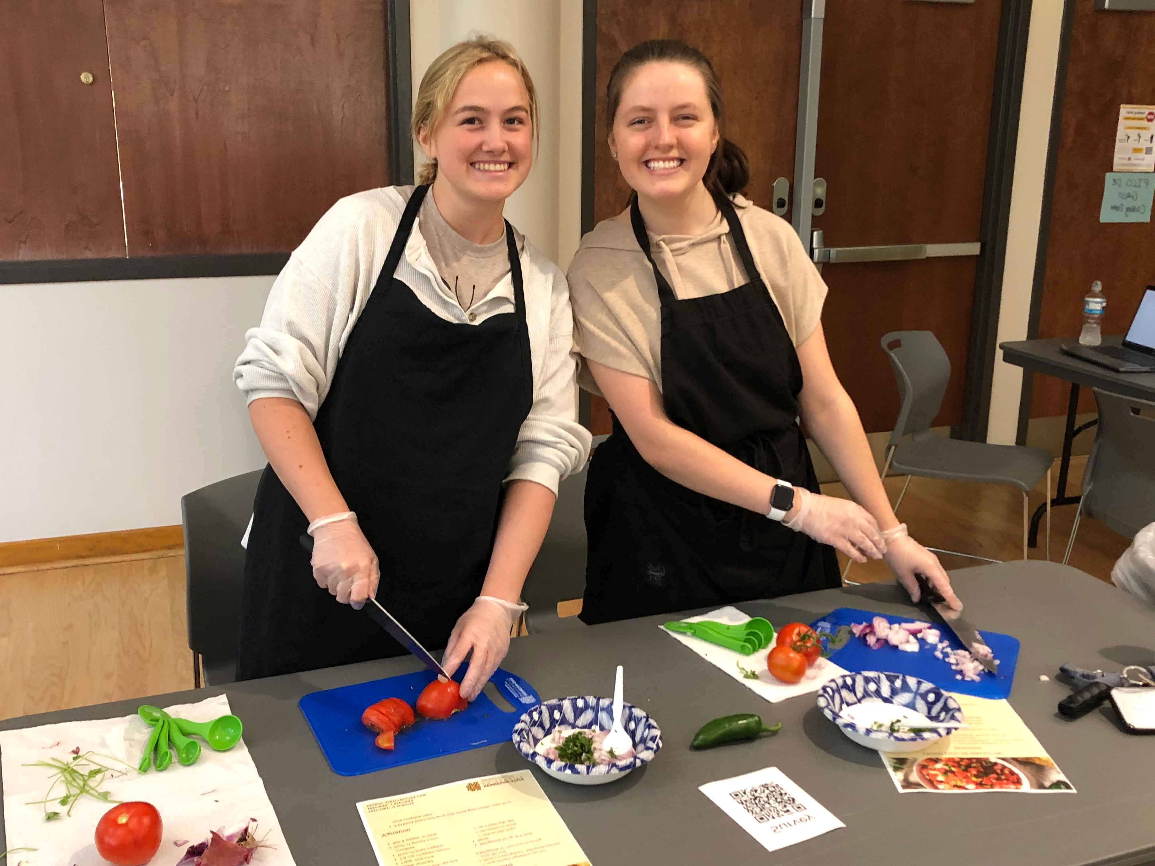  / two ksu students chopping up tomatoes.